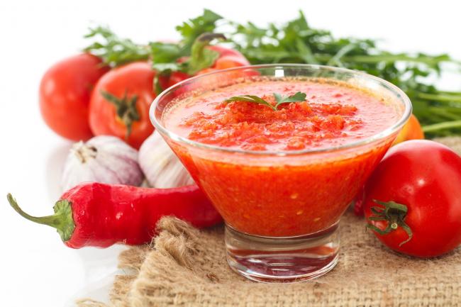 аджика в тарелке с перцем, чесноком и помидорами