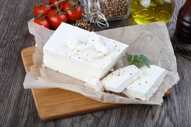 кусочек брынзы в упаковке и помидоры